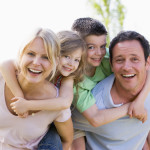 Couple giving two young children piggyback rides smiling