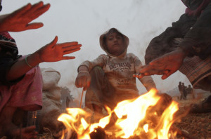 People warm themselves by a fire on a foggy winter day in Dhaka